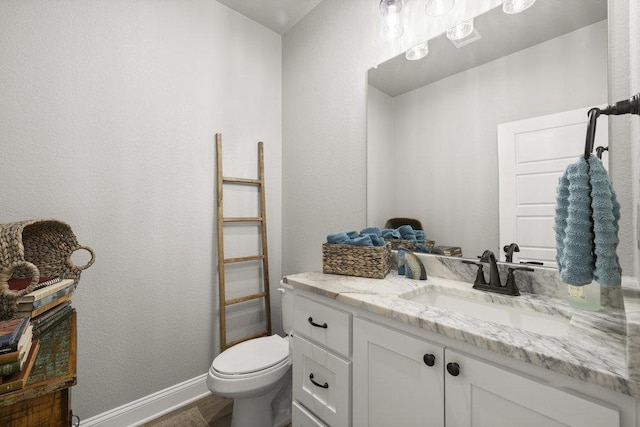 half bath featuring baseboards, toilet, vanity, and wood finished floors