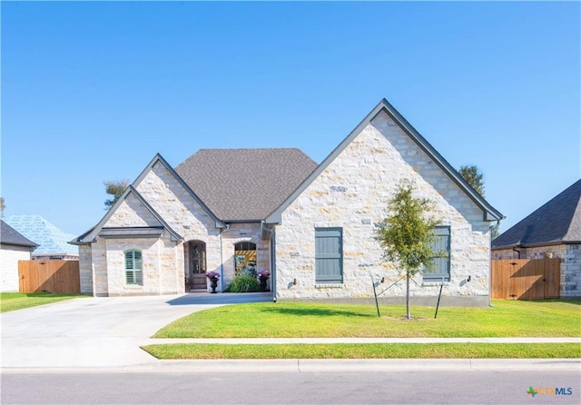 french country style house with fence, stone siding, and a front yard