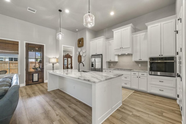 kitchen featuring white cabinets, stainless steel appliances, visible vents, a sink, and light wood-style floors