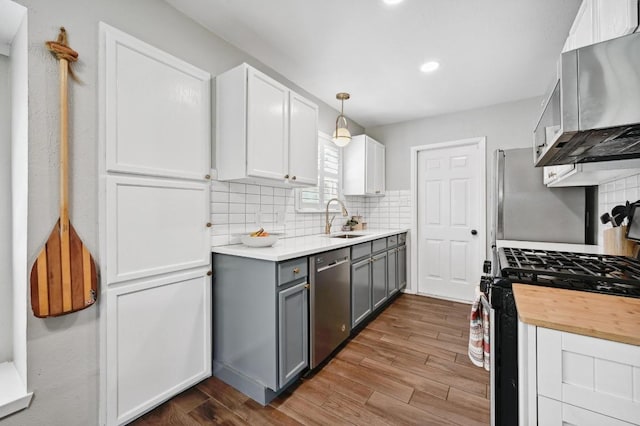 1213 S Trace Dr, Austin, TX 78745 - kitchen with tasteful backsplash, wood finished floors, a sink, appliances with stainless steel finishes, and gray cabinetry