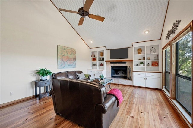 living area with high vaulted ceiling, a ceiling fan, a high end fireplace, light wood-type flooring, and baseboards