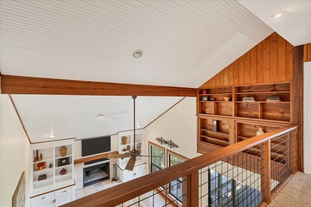 corridor featuring vaulted ceiling, wood walls, carpet, and an upstairs landing