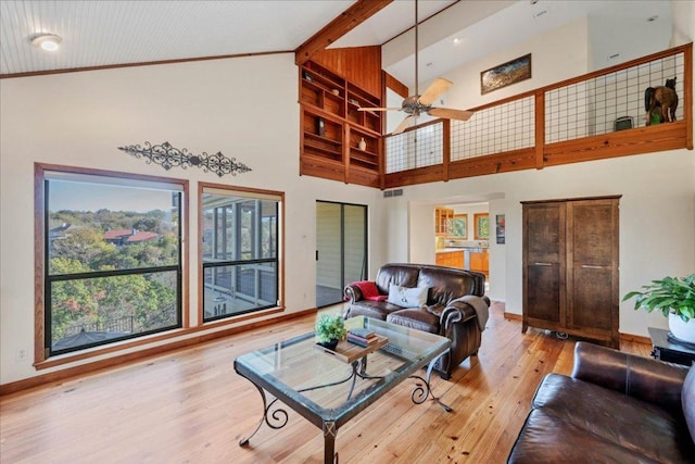 living room featuring light wood finished floors, baseboards, high vaulted ceiling, and ceiling fan