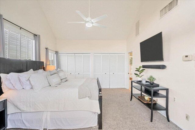 bedroom with multiple closets, visible vents, high vaulted ceiling, and carpet flooring