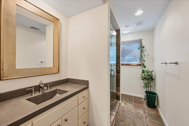 full bathroom with stone tile flooring, a stall shower, visible vents, baseboards, and vanity