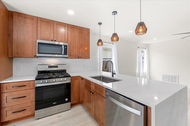 6007 Wideleaf Dr, Austin, TX 78724 - kitchen featuring a sink, brown cabinetry, visible vents, a peninsula, and appliances with stainless steel finishes