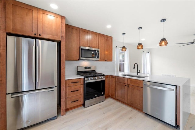 6007 Wideleaf Dr, Austin, TX 78724 - kitchen featuring a sink, brown cabinetry, light wood-style flooring, a peninsula, and appliances with stainless steel finishes