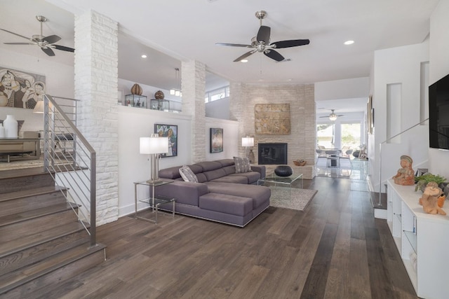 living room with stairs, a ceiling fan, wood finished floors, and a fireplace