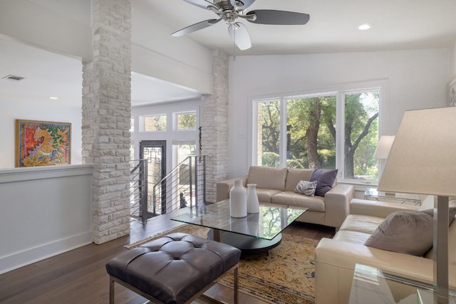 living room with baseboards, wood finished floors, visible vents, and decorative columns
