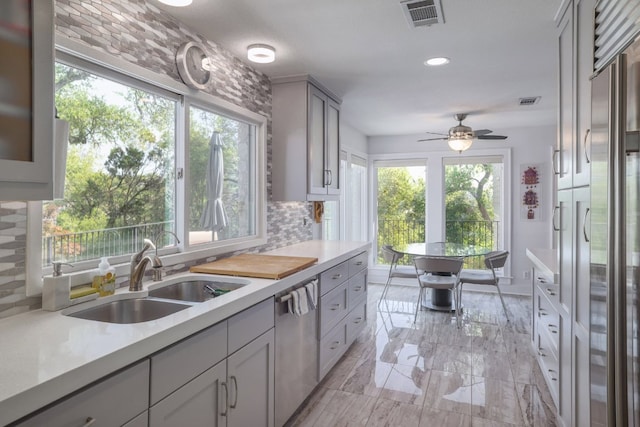 kitchen with a sink, tasteful backsplash, visible vents, dishwasher, and light countertops