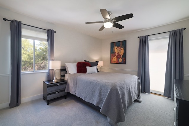 bedroom featuring baseboards, light colored carpet, and ceiling fan