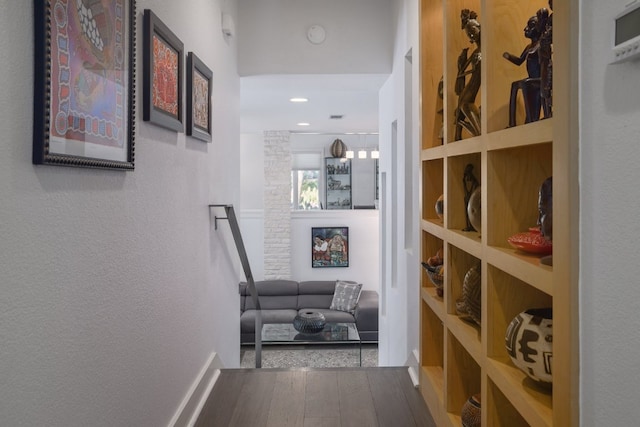 hall with a textured wall and wood finished floors