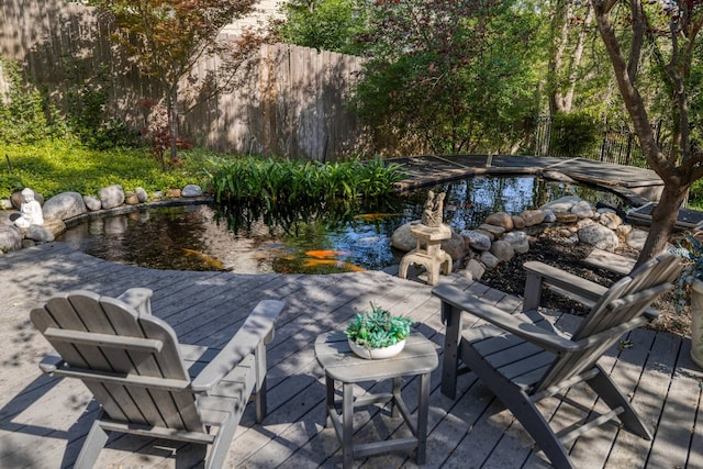wooden terrace with fence, an outdoor pool, and a small pond