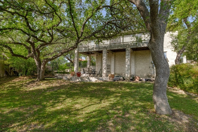 back of house with a yard, stone siding, a patio, and a deck