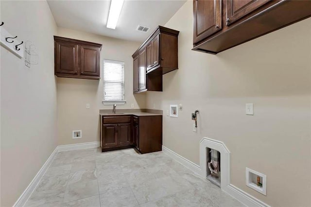 clothes washing area featuring cabinet space, washer hookup, visible vents, and baseboards