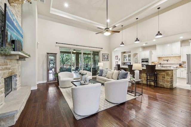 190 Estrella Xing, Georgetown, TX 78628 - living area with a stone fireplace, a ceiling fan, wood-type flooring, a towering ceiling, and baseboards