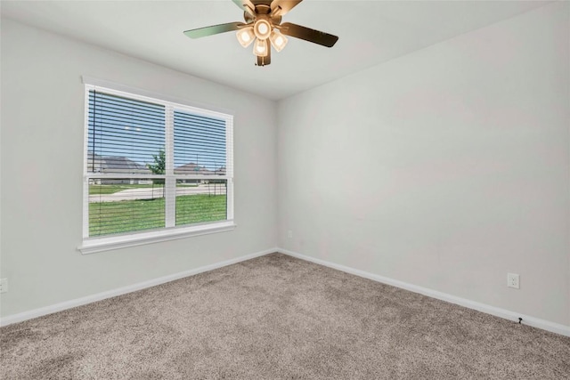 carpeted empty room featuring a ceiling fan and baseboards