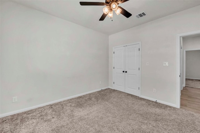 unfurnished bedroom with a closet, carpet, visible vents, a ceiling fan, and baseboards