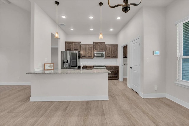 kitchen with appliances with stainless steel finishes, visible vents, a sink, dark brown cabinetry, and light wood-type flooring