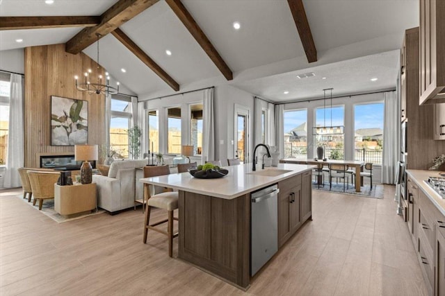 2108 Tobiano Trce, Georgetown, TX 78633 - kitchen with dishwasher, a center island with sink, light countertops, beam ceiling, and light wood-type flooring