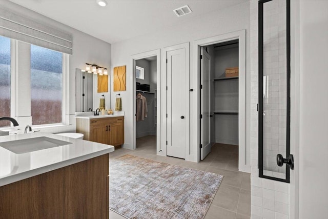 2108 Tobiano Trce, Georgetown, TX 78633 - bathroom featuring two vanities, tile patterned floors, a walk in closet, and baseboards