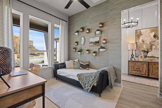 2108 Tobiano Trce, Georgetown, TX 78633 - bedroom featuring a chandelier, wood finished floors, wallpapered walls, baseboards, and an accent wall