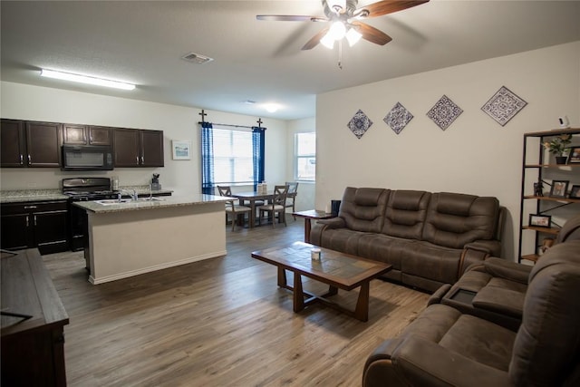 living room featuring a ceiling fan, visible vents, and dark wood-style flooring