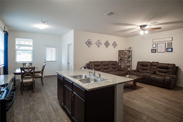 kitchen featuring range with gas stovetop, a sink, open floor plan, dark wood-type flooring, and visible vents