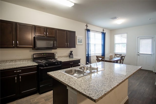 kitchen featuring a sink, visible vents, dark brown cabinetry, wood finished floors, and black appliances