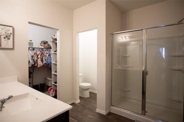 bathroom with a shower stall, toilet, vanity, and wood finished floors