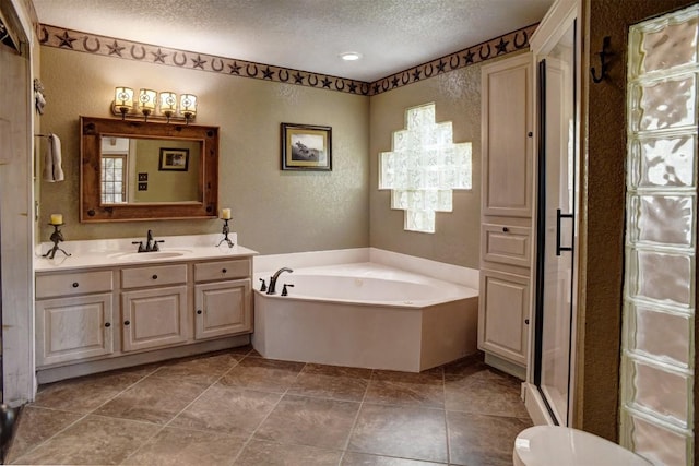 full bathroom featuring a shower stall, a garden tub, a textured ceiling, vanity, and a textured wall