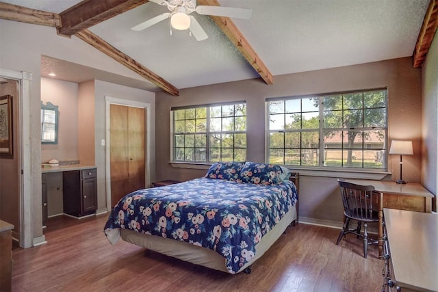 bedroom with wood finished floors, a ceiling fan, baseboards, and lofted ceiling with beams
