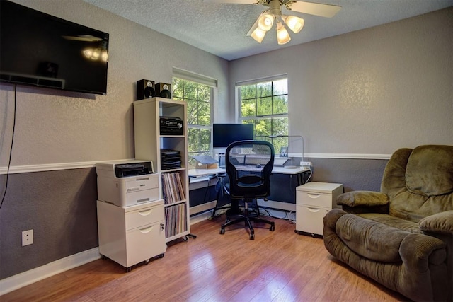 home office featuring a ceiling fan, a textured wall, and wood finished floors