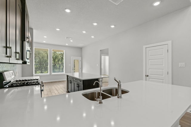 2705 Sage Ranch Dr Unit 30, Leander, TX 78641 - kitchen featuring a sink, gas stove, a center island, light countertops, and light wood finished floors