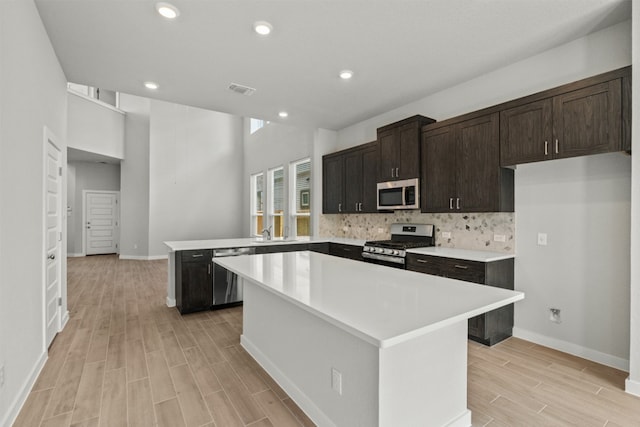 2705 Sage Ranch Dr Unit 30, Leander, TX 78641 - kitchen featuring appliances with stainless steel finishes, a peninsula, light wood-style floors, a sink, and light countertops