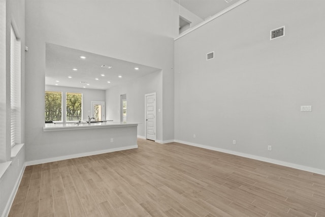 2705 Sage Ranch Dr Unit 30, Leander, TX 78641 - unfurnished living room featuring light wood-style flooring, recessed lighting, a high ceiling, and baseboards
