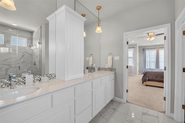 ensuite bathroom featuring a sink, a stall shower, marble finish floor, double vanity, and baseboards