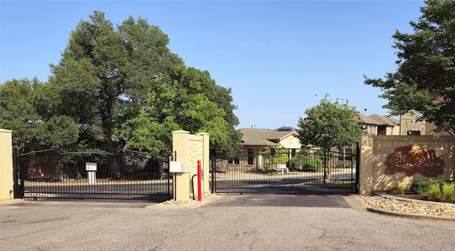 view of street featuring a gated entry, curbs, and a gate