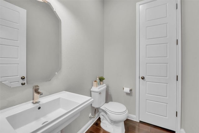 bathroom featuring toilet, wood finished floors, a sink, and baseboards