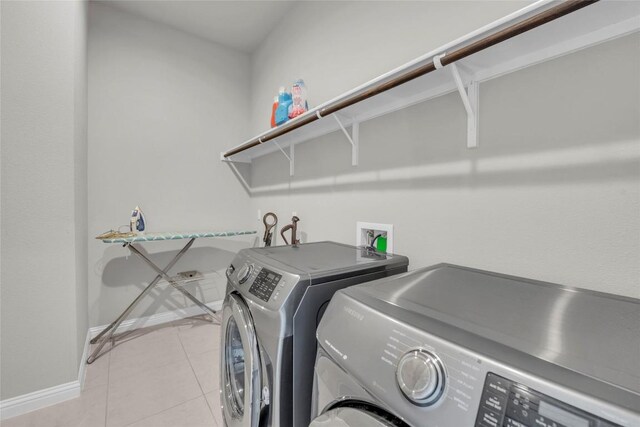 clothes washing area with baseboards, washer and clothes dryer, laundry area, and light tile patterned floors