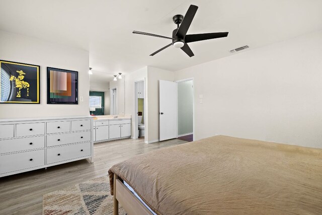 bedroom with ensuite bath, visible vents, light wood finished floors, and a ceiling fan
