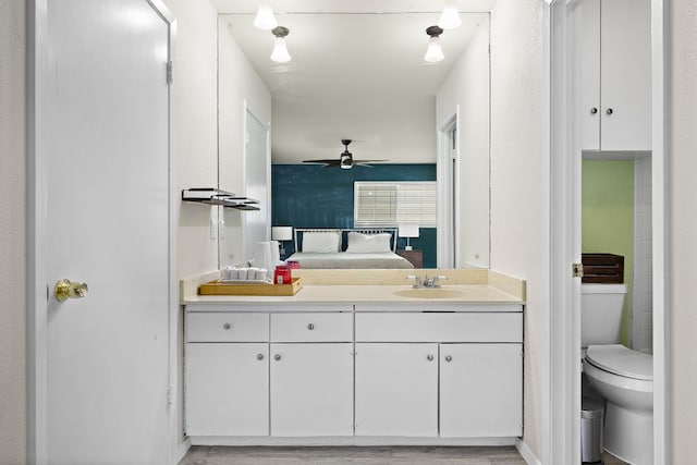 bathroom with vanity, connected bathroom, ceiling fan, and toilet
