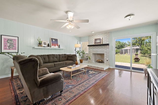 living room with a ceiling fan, wood finished floors, and a fireplace