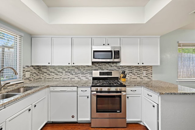 kitchen featuring white cabinets, backsplash, stainless steel appliances, and a sink