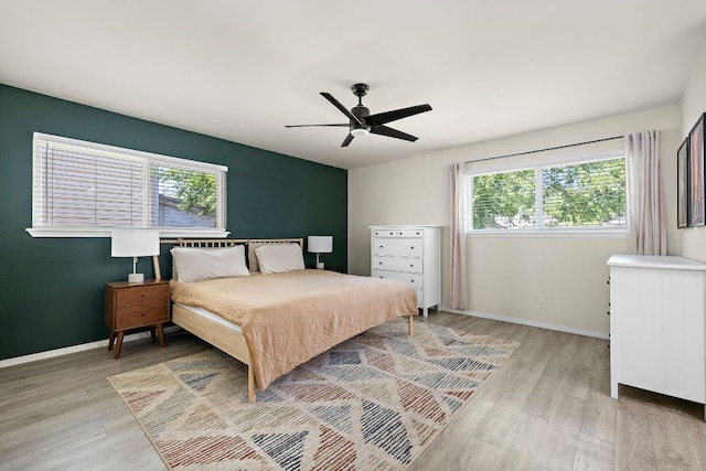 bedroom with light wood-type flooring, baseboards, and multiple windows