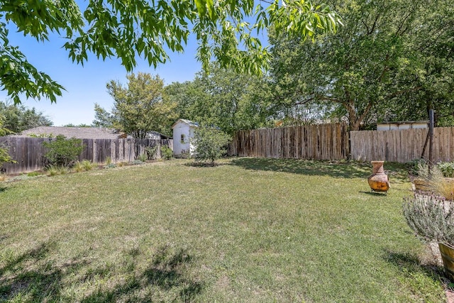 view of yard with a fenced backyard, an outdoor structure, and a storage unit