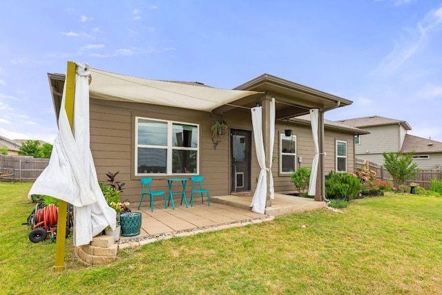 rear view of property with fence, a lawn, and a patio