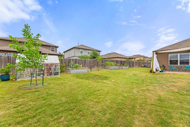 view of yard with a garden, a fenced backyard, and a patio area