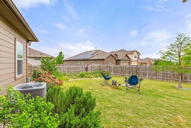 view of yard with a fenced backyard, a residential view, and central AC unit
