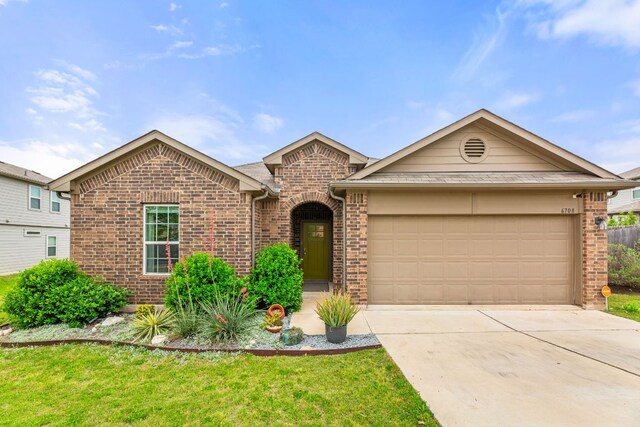 single story home with a front yard, concrete driveway, an attached garage, and brick siding